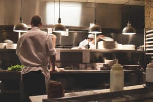 Chefs working at the pass in a professional kitchen under warm pendant lights