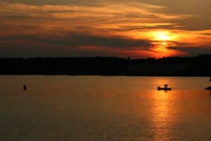 Autumn on Lake Wylie: Why the Quiet Season Might Be the Best One featured image Sunset over Lake Wylie with a small fishing boat silhouetted on golden water. Autumn Weekend Getaway